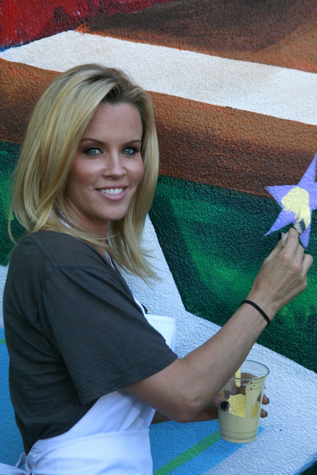 Jenny McCarthy, gray t-shirt, white apron, paintbrush, ponytail holder, black bracelet, paint cup